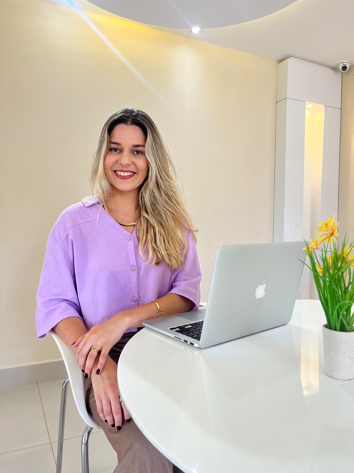 Vivane Menezes, psicóloga, sorrindo em seu consultório com laptop